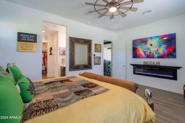 bedroom featuring ensuite bath, wood-type flooring, and ceiling fan with notable chandelier