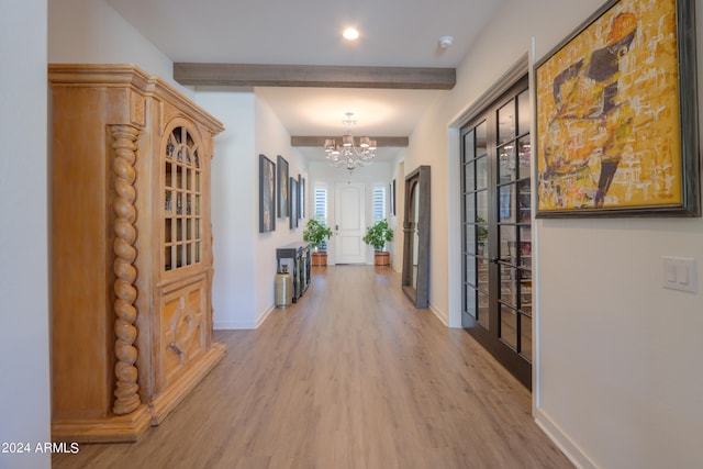 hallway with beamed ceiling, hardwood / wood-style floors, and a chandelier