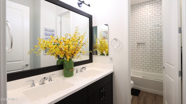 full bathroom with vanity, tiled shower / bath combo, hardwood / wood-style flooring, and toilet