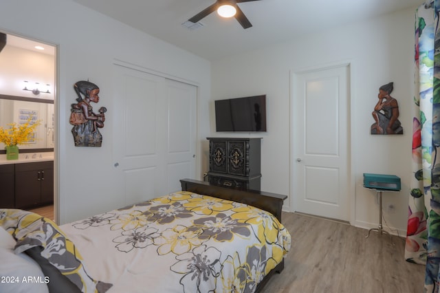 bedroom featuring light hardwood / wood-style floors, a closet, ensuite bath, and ceiling fan