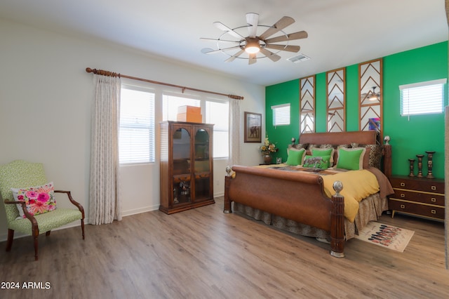 bedroom with ceiling fan, multiple windows, and hardwood / wood-style floors