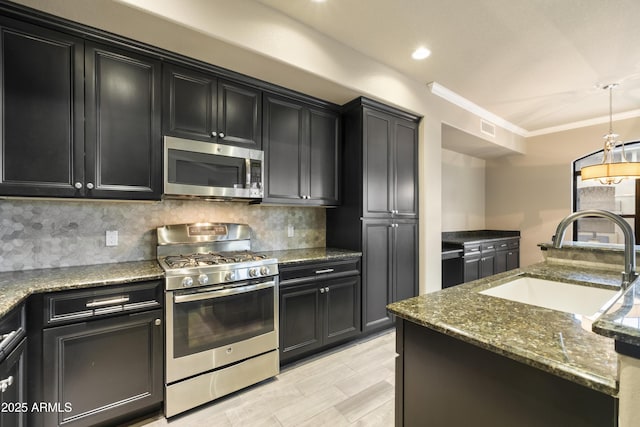 kitchen with decorative backsplash, dark cabinets, appliances with stainless steel finishes, and a sink