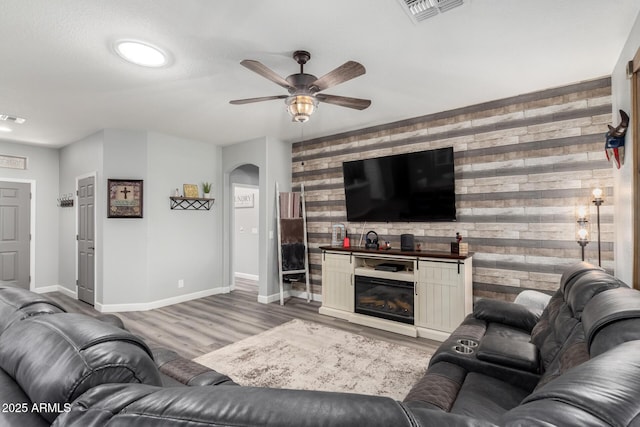 2910 S Olivewood, Mesa, AZ 85212 - living room with an accent wall, wooden walls, arched walkways, a ceiling fan, and baseboards