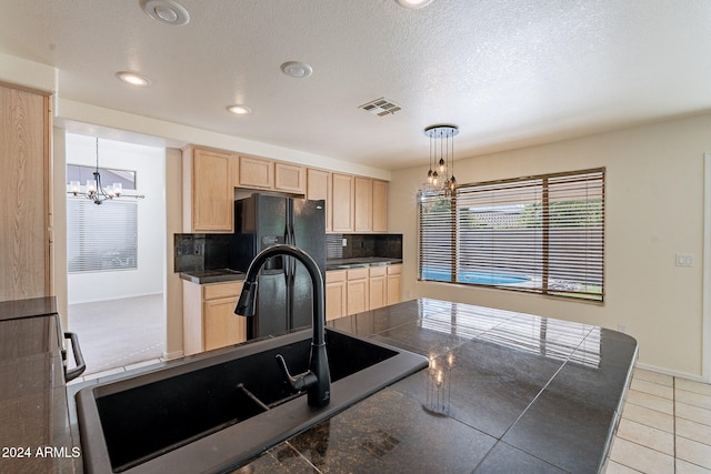 kitchen featuring tasteful backsplash, decorative light fixtures, a textured ceiling, light brown cabinetry, and sink