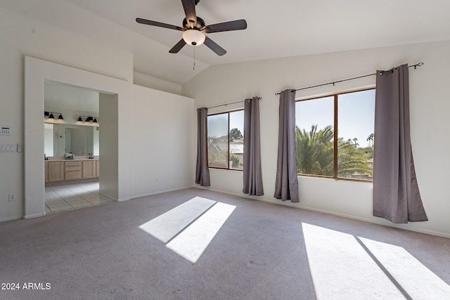 spare room featuring ceiling fan, light colored carpet, plenty of natural light, and lofted ceiling