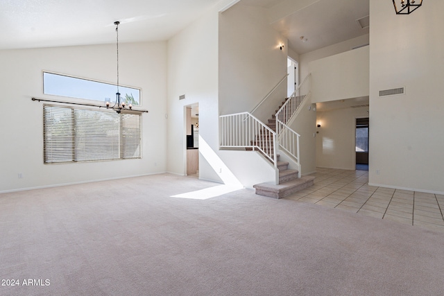 unfurnished living room with high vaulted ceiling, an inviting chandelier, and light carpet