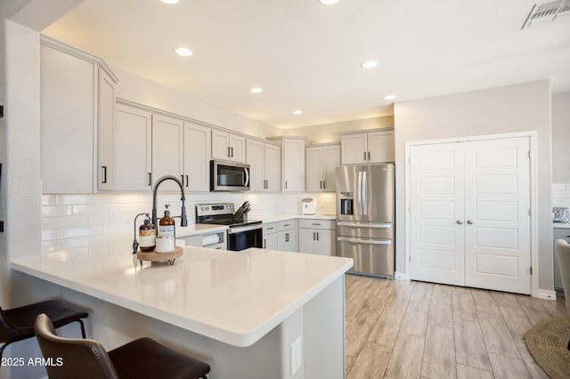 3523 W Rhapsody Dr, Sierra Vista, AZ 85650 - kitchen with visible vents, a peninsula, a kitchen bar, light countertops, and appliances with stainless steel finishes