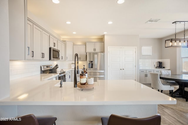 3523 W Rhapsody Dr, Sierra Vista, AZ 85650 - kitchen featuring visible vents, a peninsula, light countertops, appliances with stainless steel finishes, and backsplash