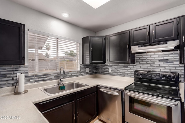 kitchen with stainless steel appliances, a sink, under cabinet range hood, backsplash, and light countertops