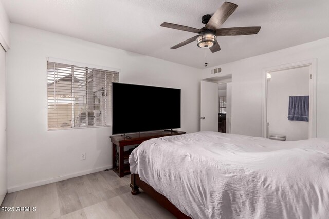 bedroom with wood finished floors, baseboards, ceiling fan, and ensuite bathroom