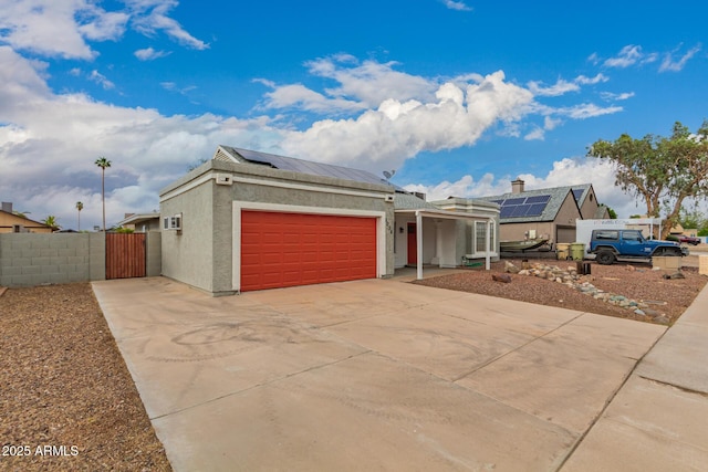ranch-style house featuring driveway, stucco siding, solar panels, a garage, and a gate
