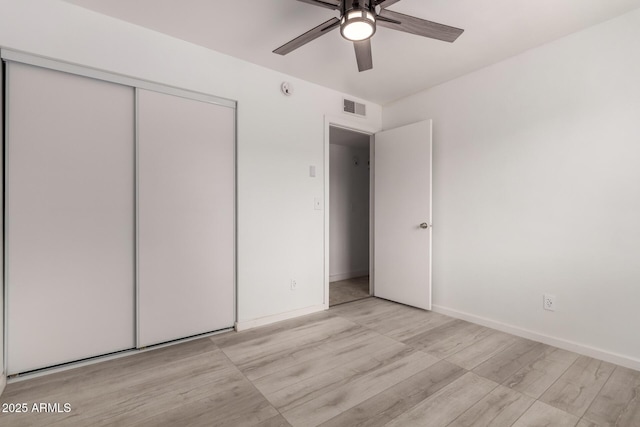 unfurnished bedroom featuring light wood finished floors, a closet, baseboards, and a ceiling fan