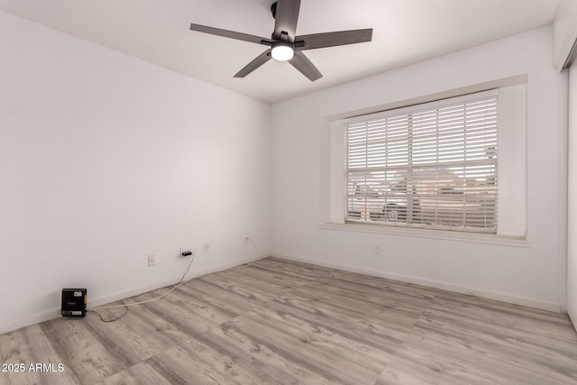 empty room with a ceiling fan, wood finished floors, and baseboards