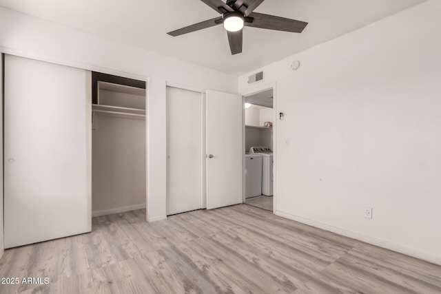 unfurnished bedroom with washer and dryer, two closets, light wood-style floors, and baseboards