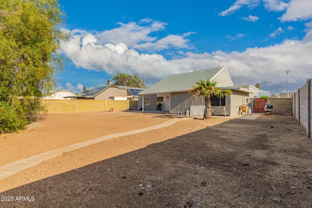rear view of property featuring stucco siding and a fenced backyard