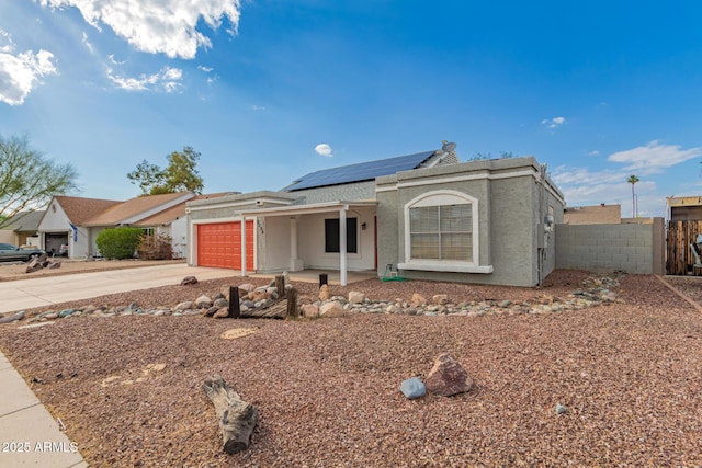 single story home with an attached garage, solar panels, fence, driveway, and stucco siding