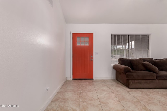 foyer with vaulted ceiling, baseboards, and light tile patterned flooring