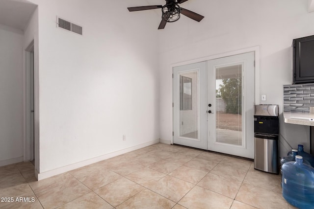 entryway with french doors, ceiling fan, a towering ceiling, light tile patterned floors, and baseboards
