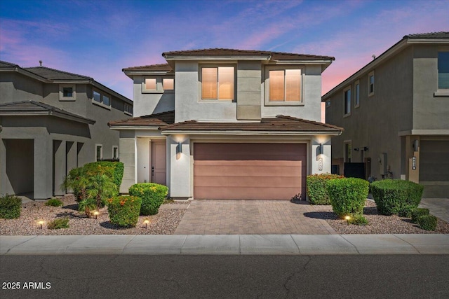 view of front of property with an attached garage, stucco siding, decorative driveway, and a tile roof