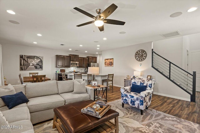 living area featuring recessed lighting, wood finished floors, a ceiling fan, baseboards, and stairway