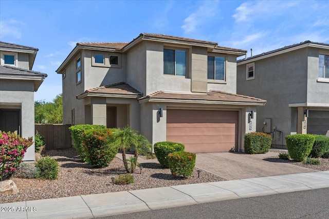 view of front of house with a garage, stucco siding, decorative driveway, fence, and a tile roof