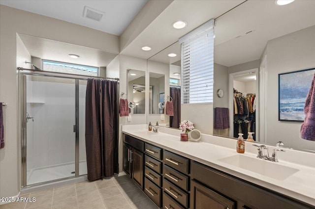 full bath featuring a shower stall, double vanity, tile patterned floors, a spacious closet, and recessed lighting