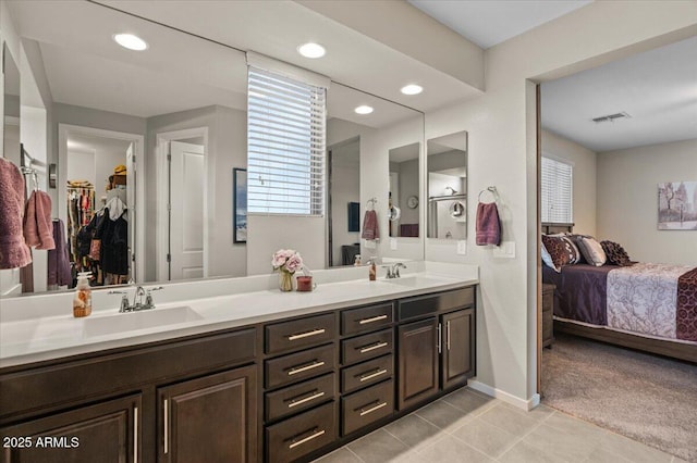 ensuite bathroom with tile patterned floors, double vanity, recessed lighting, baseboards, and a walk in closet