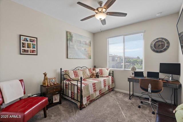 carpeted bedroom with an office area, baseboards, and a ceiling fan