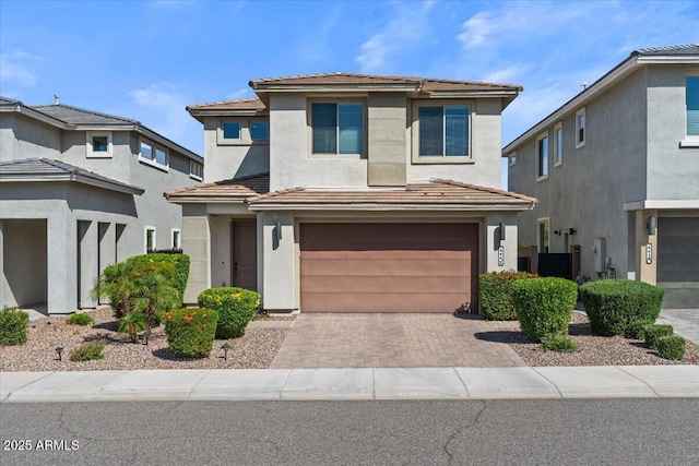 view of front of home with a garage, stucco siding, decorative driveway, and a tile roof