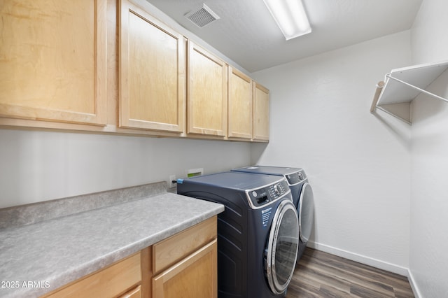 laundry room featuring dark wood-type flooring, cabinets, and washer and clothes dryer