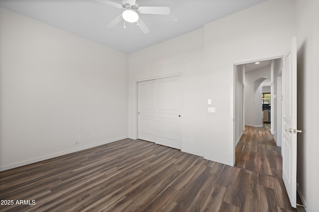 unfurnished bedroom featuring dark wood-type flooring, ceiling fan, and a closet