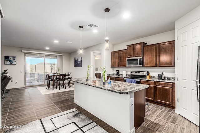 kitchen featuring appliances with stainless steel finishes, dark brown cabinets, sink, pendant lighting, and an island with sink