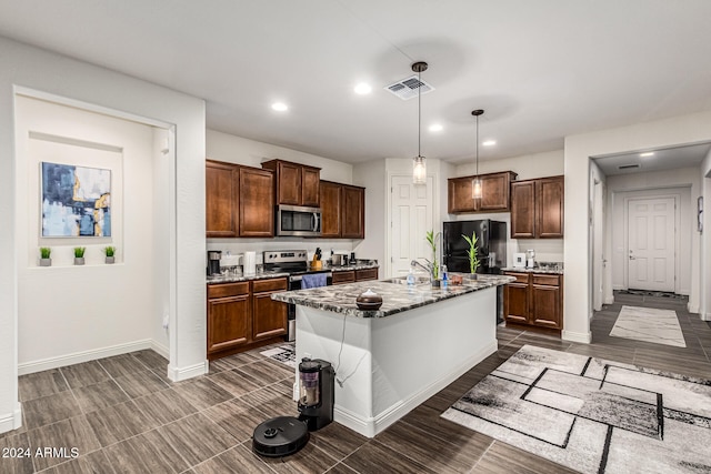 kitchen with dark hardwood / wood-style flooring, decorative light fixtures, a breakfast bar area, a center island with sink, and appliances with stainless steel finishes