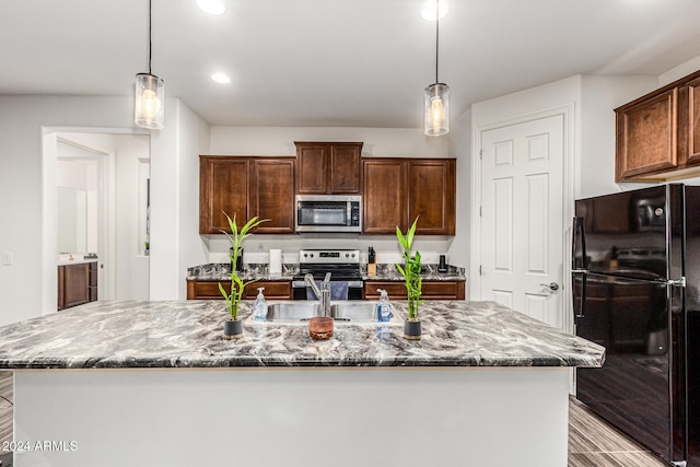 kitchen featuring light stone countertops, stainless steel appliances, sink, pendant lighting, and an island with sink