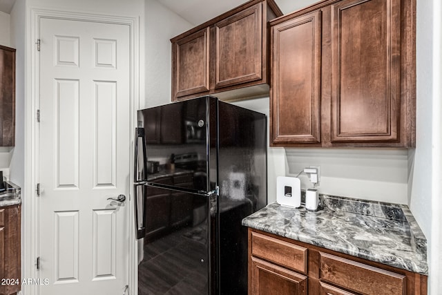 kitchen featuring stone counters and black refrigerator