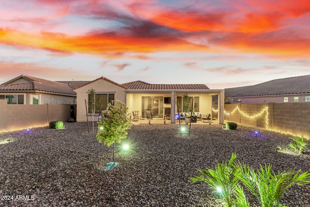 back house at dusk featuring a patio