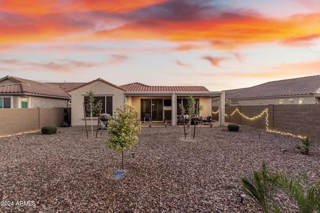 back house at dusk featuring a patio area