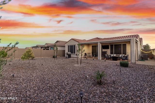 back house at dusk with an outdoor living space, a patio, and central AC unit