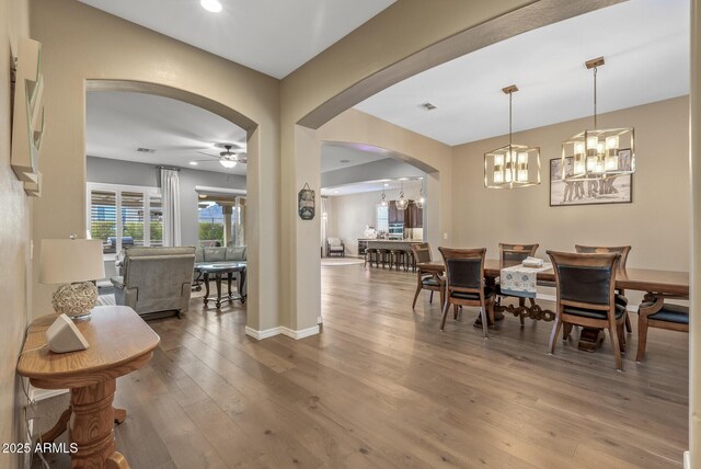 dining space with hardwood / wood-style floors and ceiling fan with notable chandelier