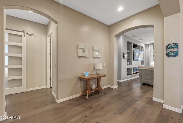 hall with dark hardwood / wood-style floors, a barn door, and built in features