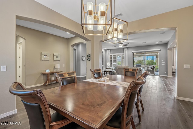 dining space with dark hardwood / wood-style flooring and ceiling fan with notable chandelier