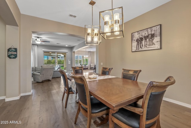 dining room featuring ceiling fan with notable chandelier and hardwood / wood-style flooring