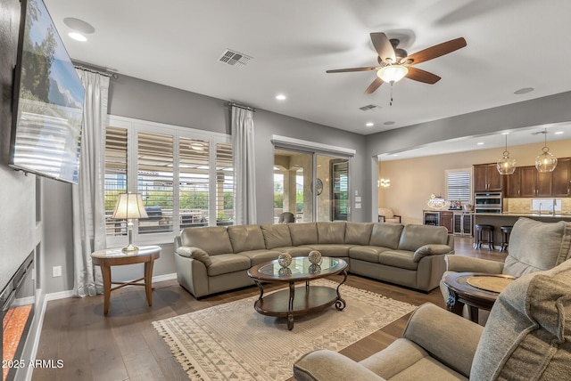 living room featuring ceiling fan and dark wood-type flooring