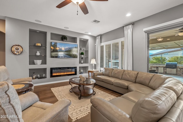 living room featuring hardwood / wood-style flooring, built in features, and ceiling fan