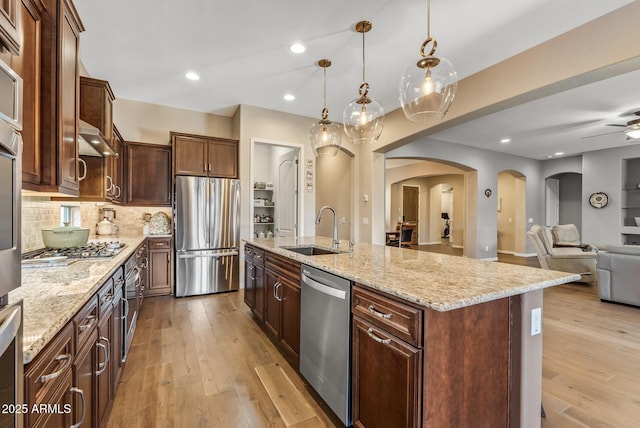 kitchen with a large island, sink, hanging light fixtures, tasteful backsplash, and appliances with stainless steel finishes