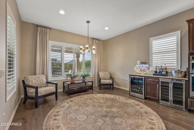 living area featuring a chandelier, dark hardwood / wood-style floors, wine cooler, and bar