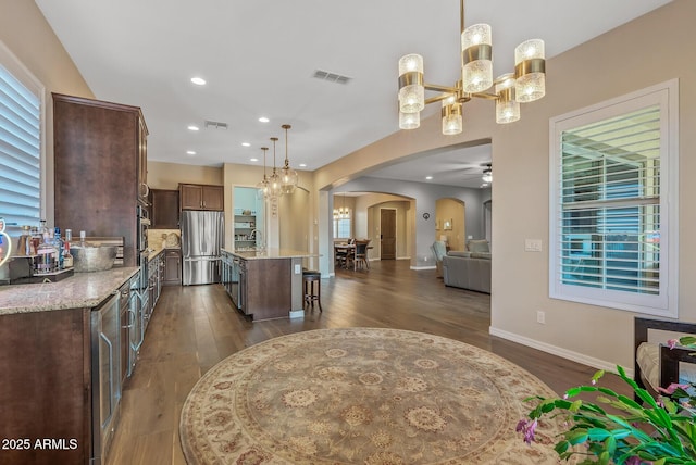 kitchen with a center island, ceiling fan with notable chandelier, hanging light fixtures, dark hardwood / wood-style floors, and stainless steel appliances