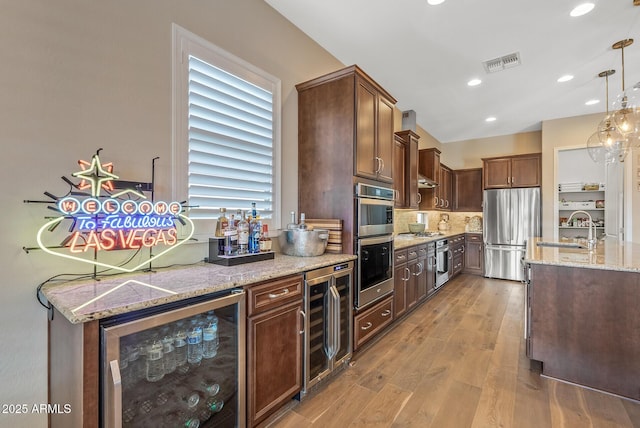 kitchen with beverage cooler, sink, hanging light fixtures, and appliances with stainless steel finishes