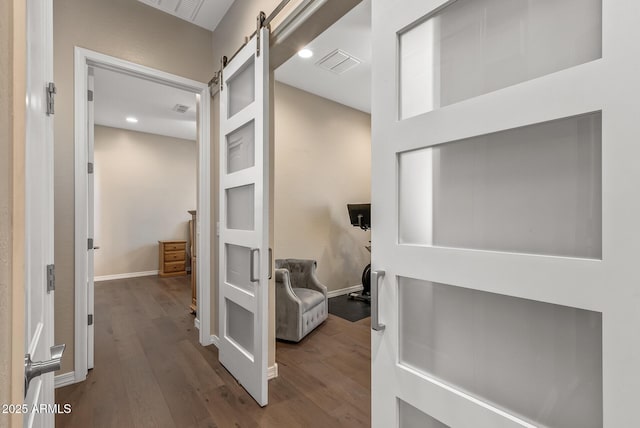 hallway with a barn door and wood-type flooring