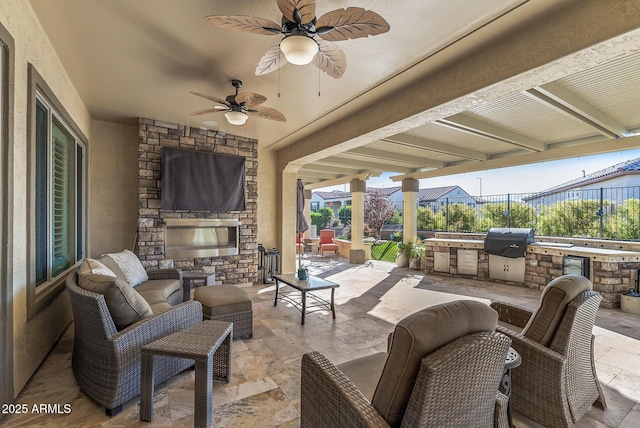 view of patio / terrace featuring an outdoor stone fireplace, a grill, exterior kitchen, and ceiling fan